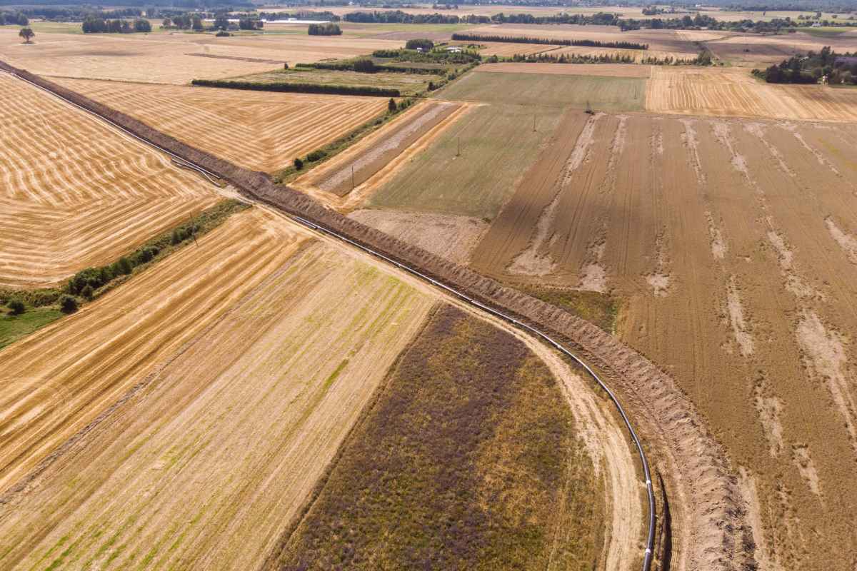 Dideli žemės ūkio laukai su vamzdynu per juos