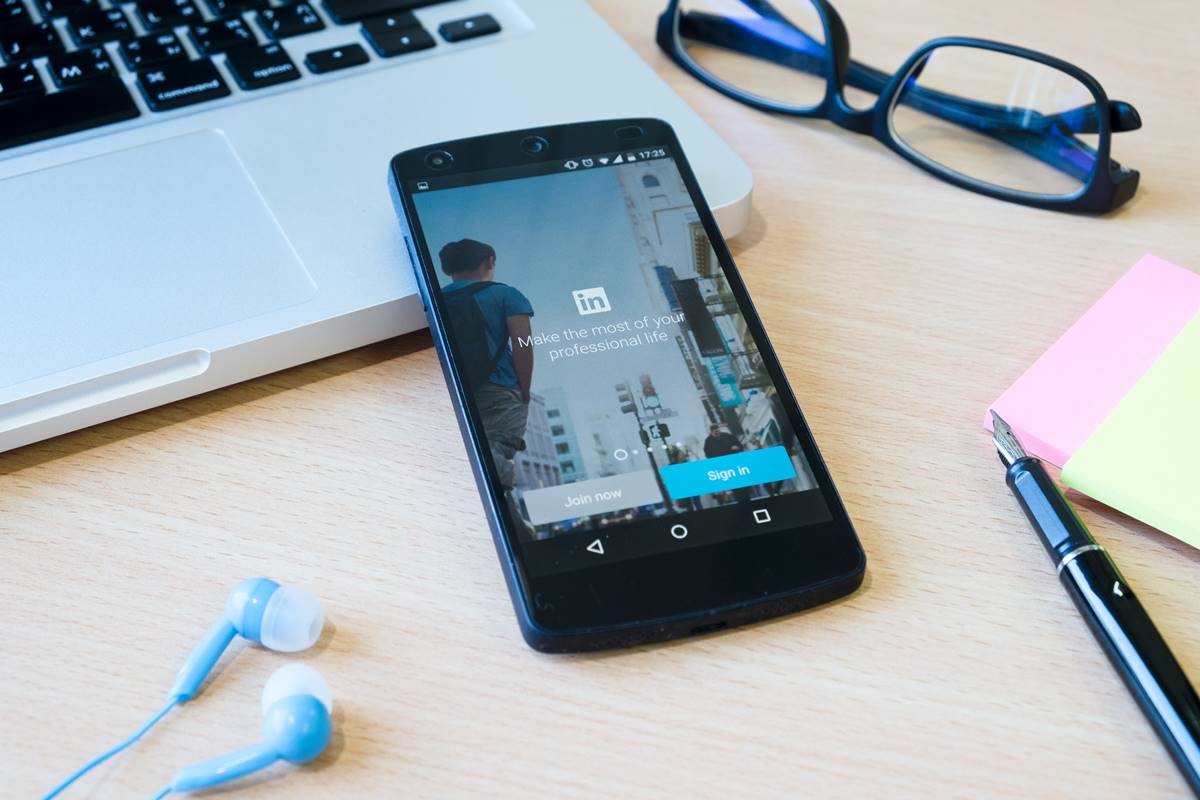Professional using the LinkedIn mobile app on a smartphone, illustrating a LinkedIn personal branding strategy.